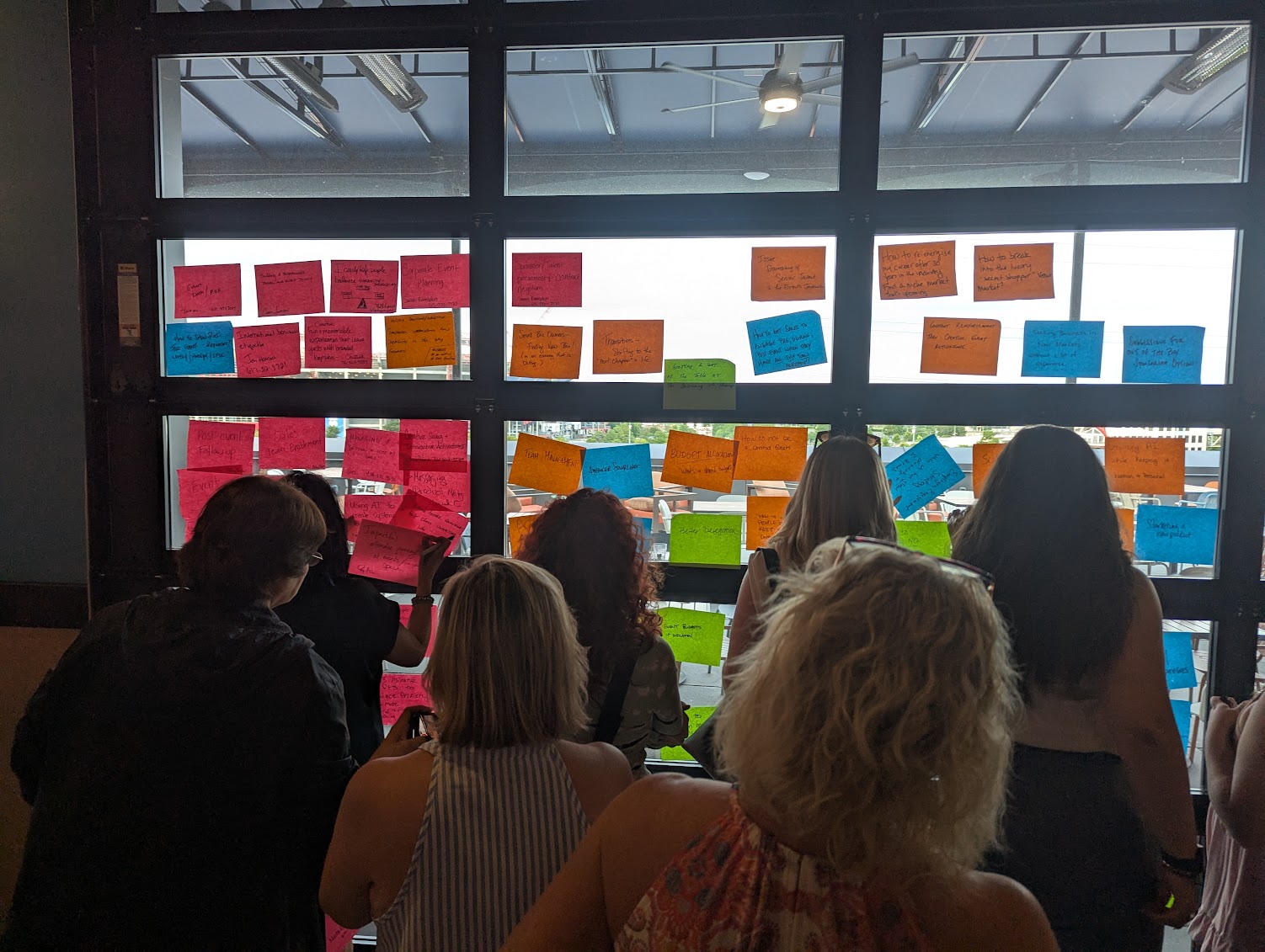 Attendees adding sticky notes to a glass wall during the agenda build.