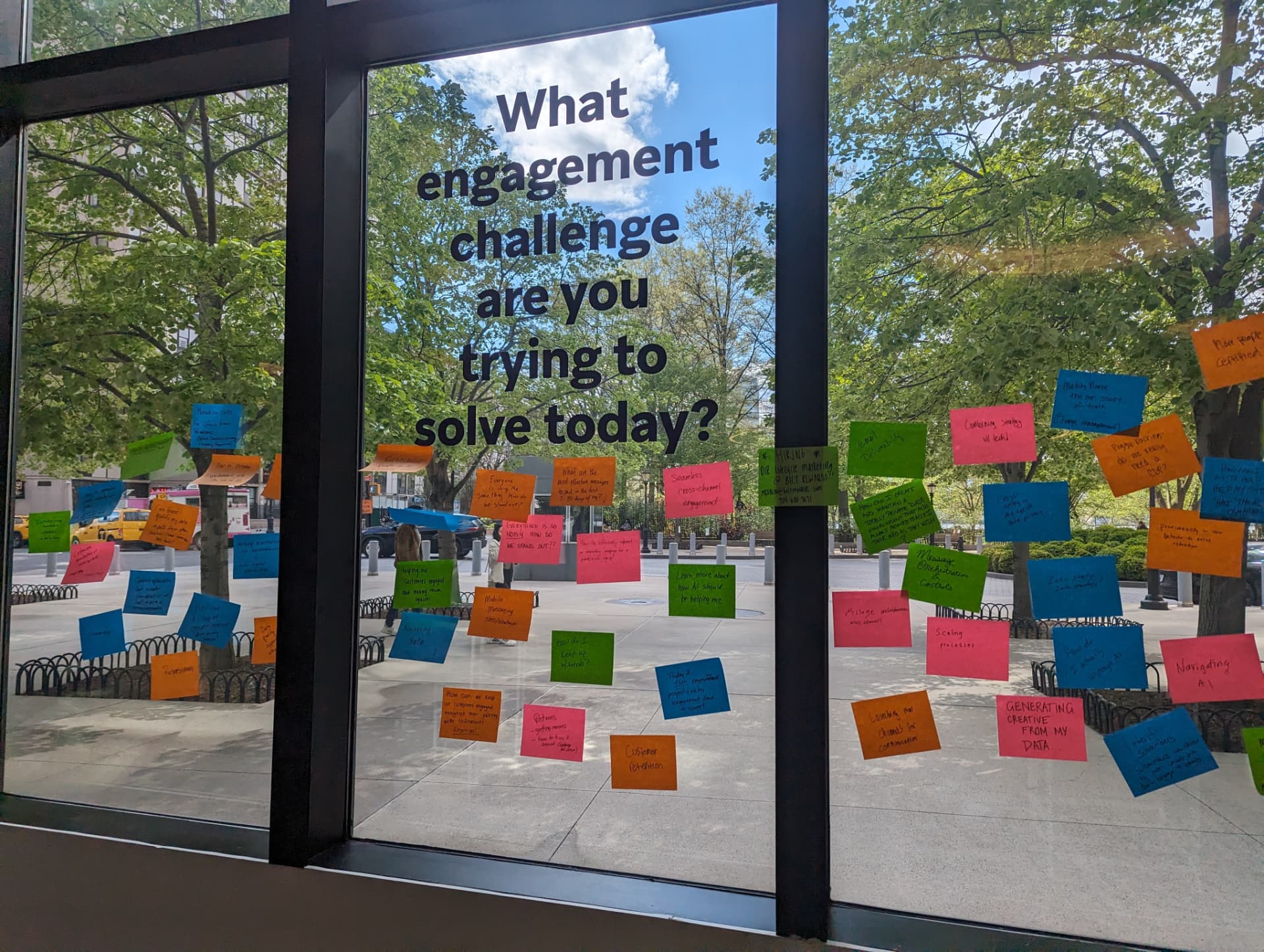 A glass window covered in handwritten sticky notes, under the question 'What engagement challenge are you trying to solve today?'