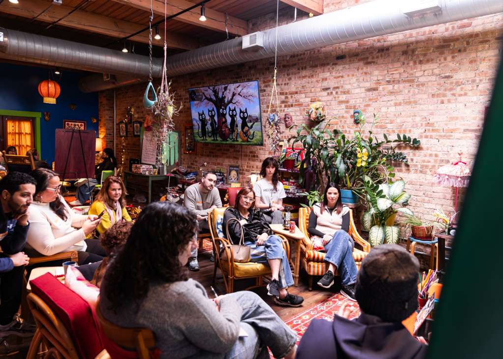 An audience listening intently in a plant-filled loft space.
