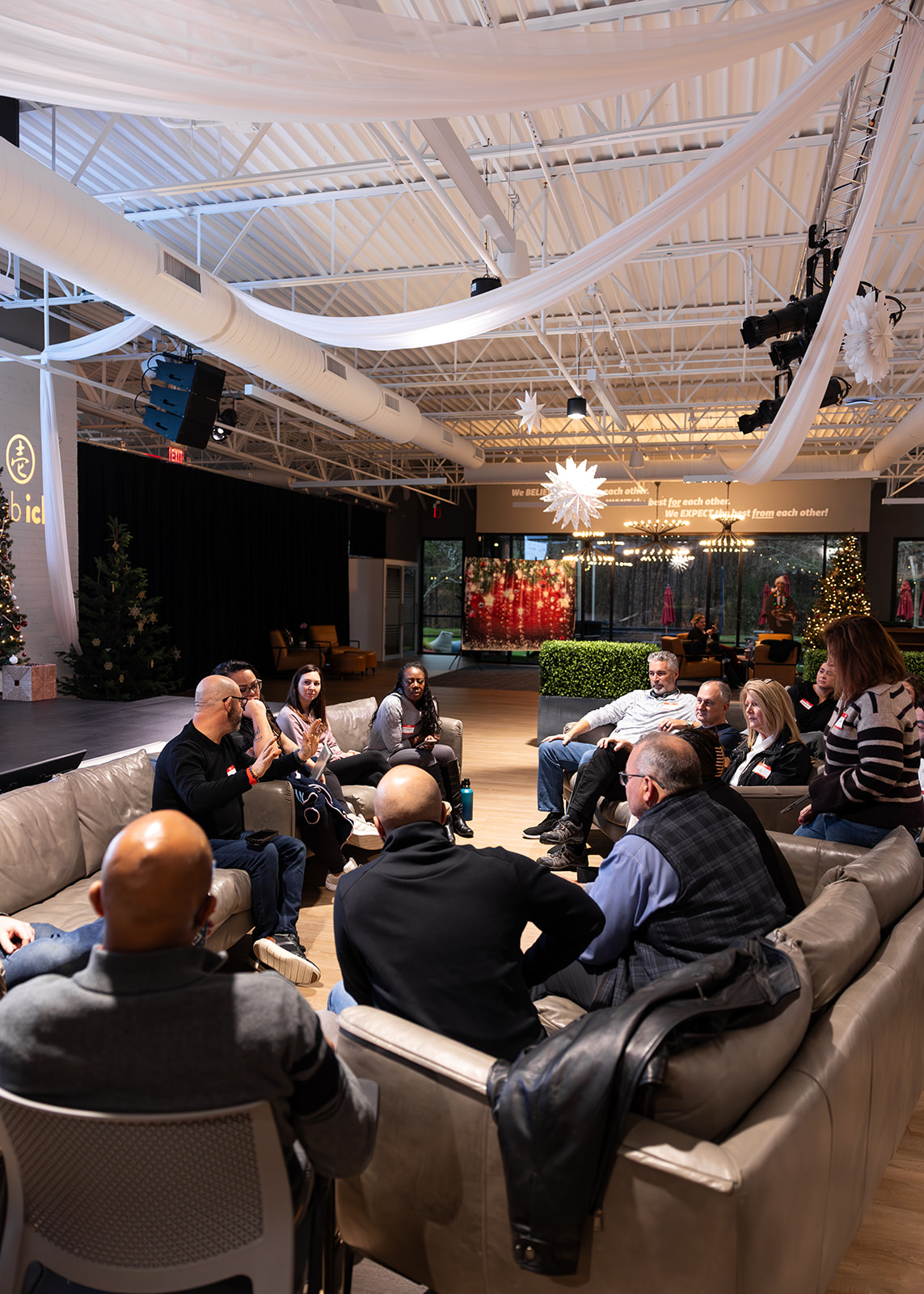 A group seated on sofas in a circle, mid-conversation.