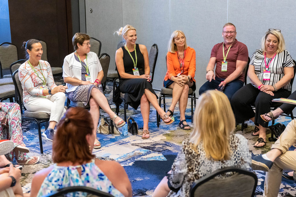 Attendees seated in a circle, laughing during a breakout session.